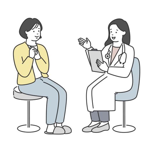 向かい合ってイスに座る、診察を受けて安心する女性の患者(左側)と、女性医師(右側)